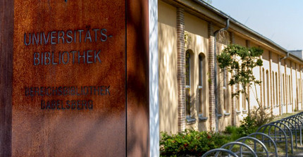 Flat, elongated building, on the left in the foreground a metal column with the lettering "Universitätsbibliothek Bereichsbibliothek Babelsberg".